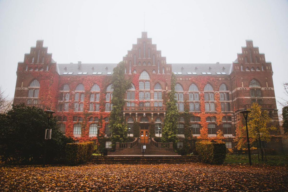Historic Lund University Library facade with autumn foliage and fog, Sweden.