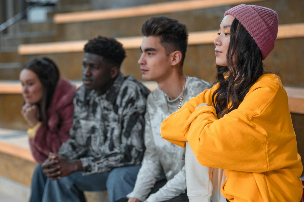 A group of diverse young adults sitting on steps, showcasing friendship.