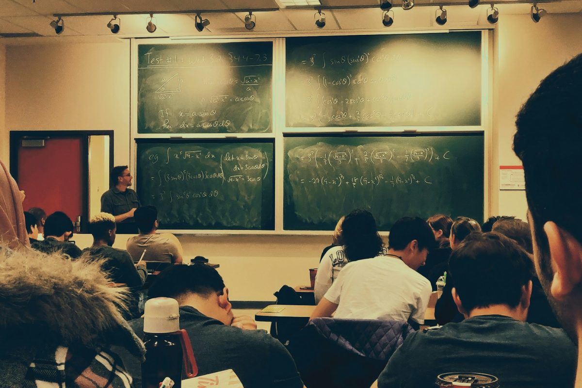 student sitting on chairs in front of chalkboard